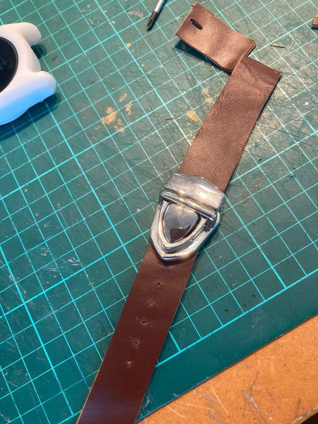 Leather strap being cut on a mat